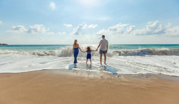 man, woman and child holding hands on seashore